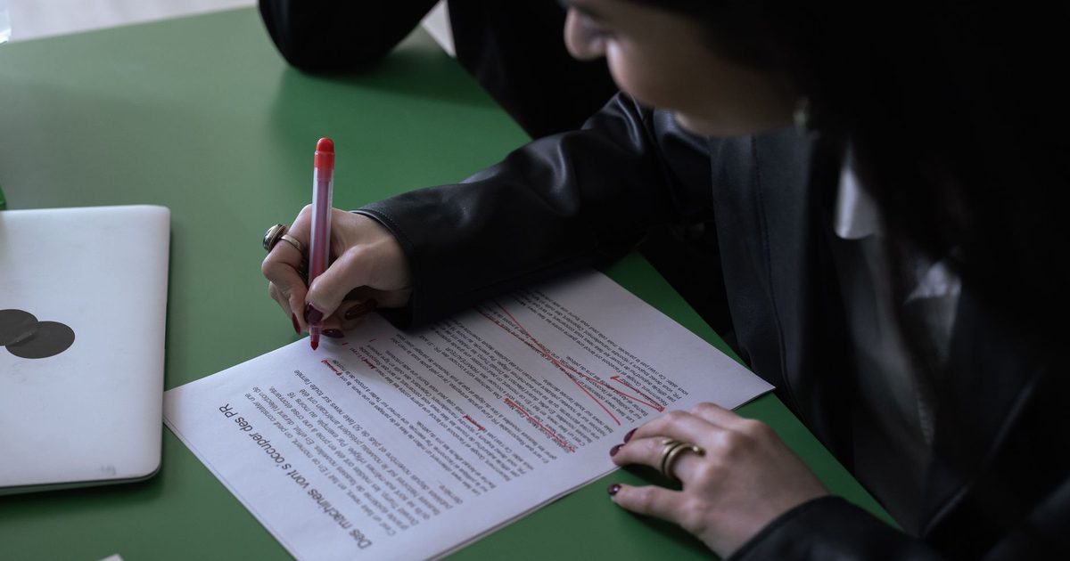 Person korrigiert ein gedrucktes Dokument mit rotem Stift